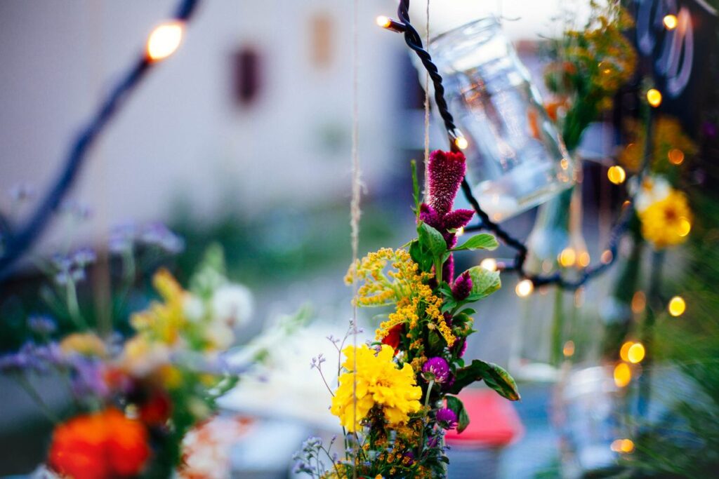 Blumen und Lichter schmücken eine sommerliche Dekoration zur Sommersonnenwende im warmen Abendlicht.
