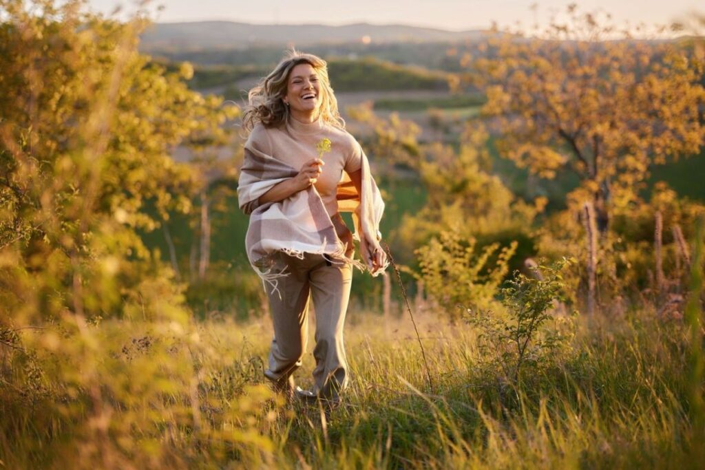 Frau bei einem Spaziergang durch eine spätsommerliche Landschaft im warmen Abendlicht